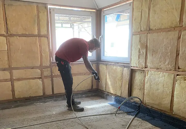 720 x 500 Ginnerup Mand påfører flydende dampapærre på betongulv med airless sprøjteanlæg